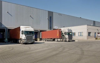 Camiones efectuando la descarga de mercancías en los muelles del almacén