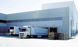 Camiones de mercancías descargan en el almacén como parte de las operaciones de cross-docking