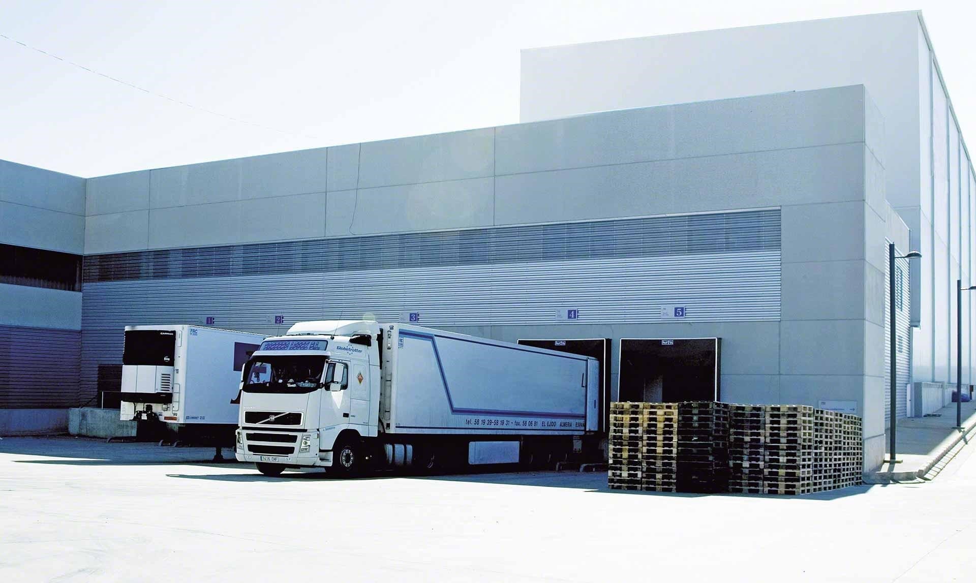 Camiones de mercancías descargan en el almacén como parte de las operaciones de cross-docking Camiones de mercancías descargan en el almacén como parte de las operaciones de cross-docking