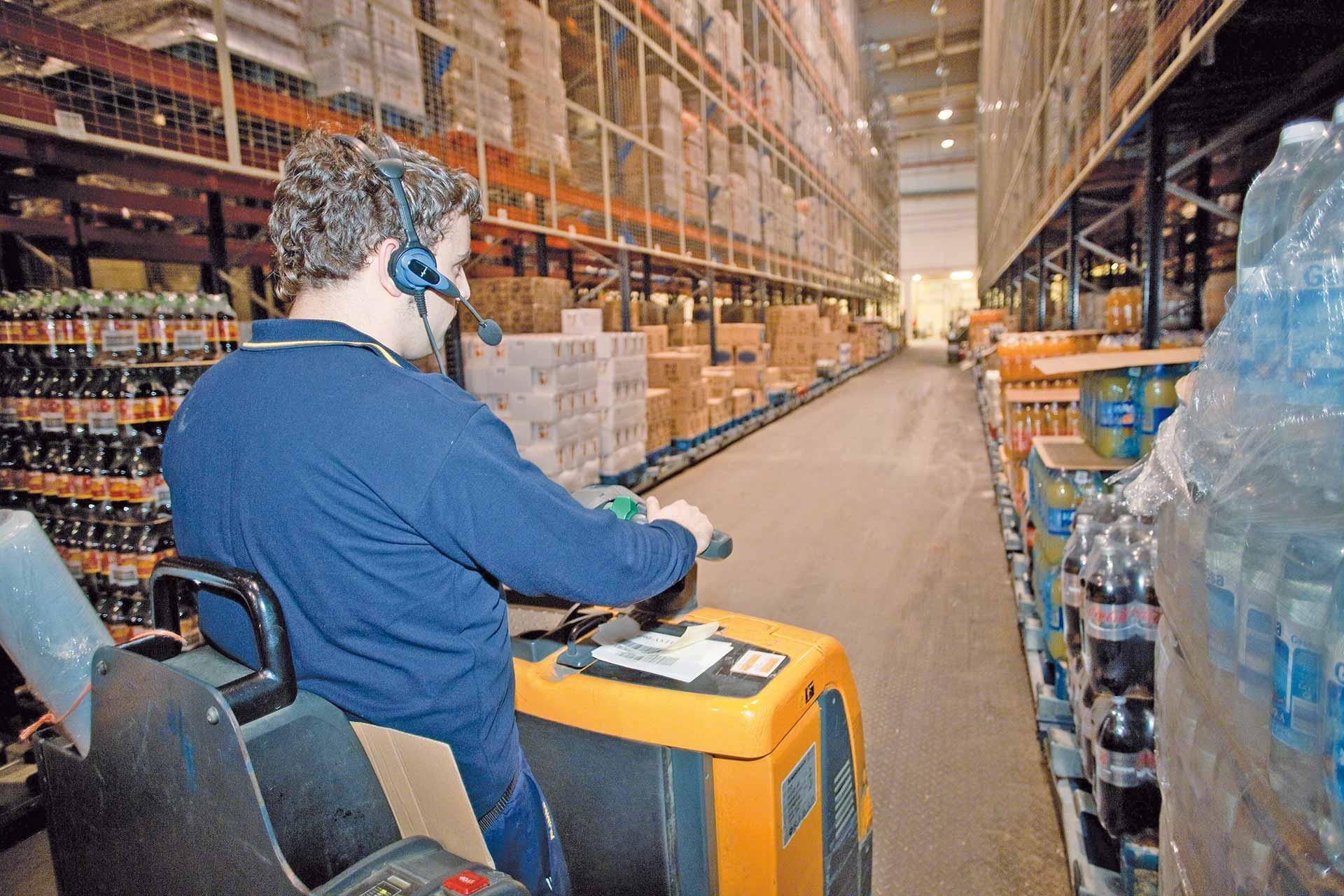 Un operario prepara pedidos en cajas asistido por un sistema de picking por voz Un operario prepara pedidos en cajas asistido por un sistema de picking por voz