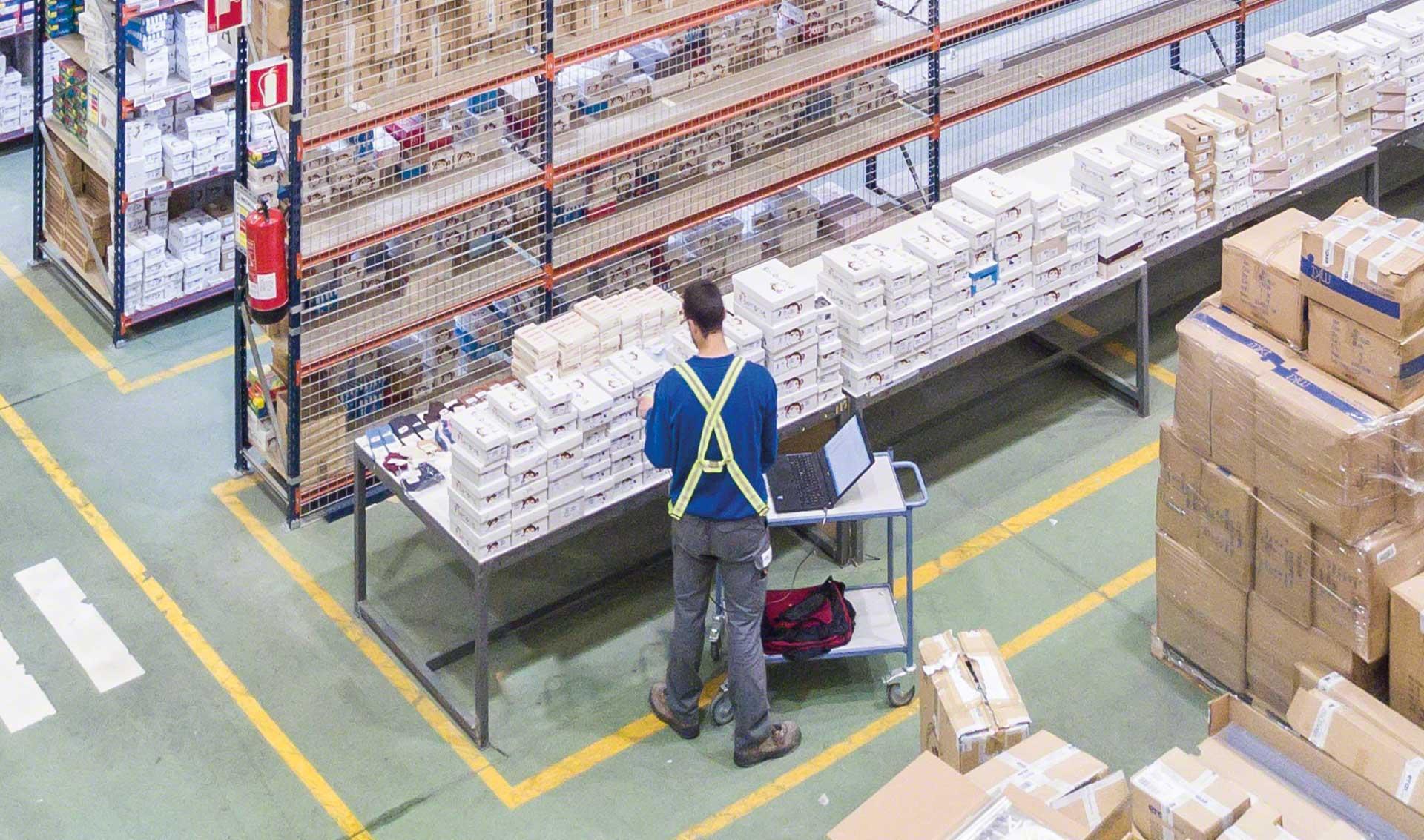 Un trabajador revisa los productos de un almacén con la ayuda de un dispositivo electrónico Un trabajador revisa los productos de un almacén con la ayuda de un dispositivo electrónico