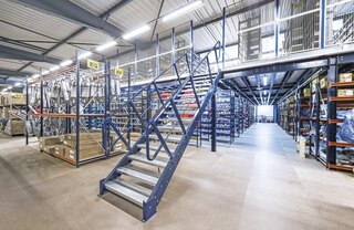 El acceso a la parte superior de un altillo metálico se realiza mediante escaleras, que pueden ubicarse lateral o frontalmente, en función del diseño del almacén